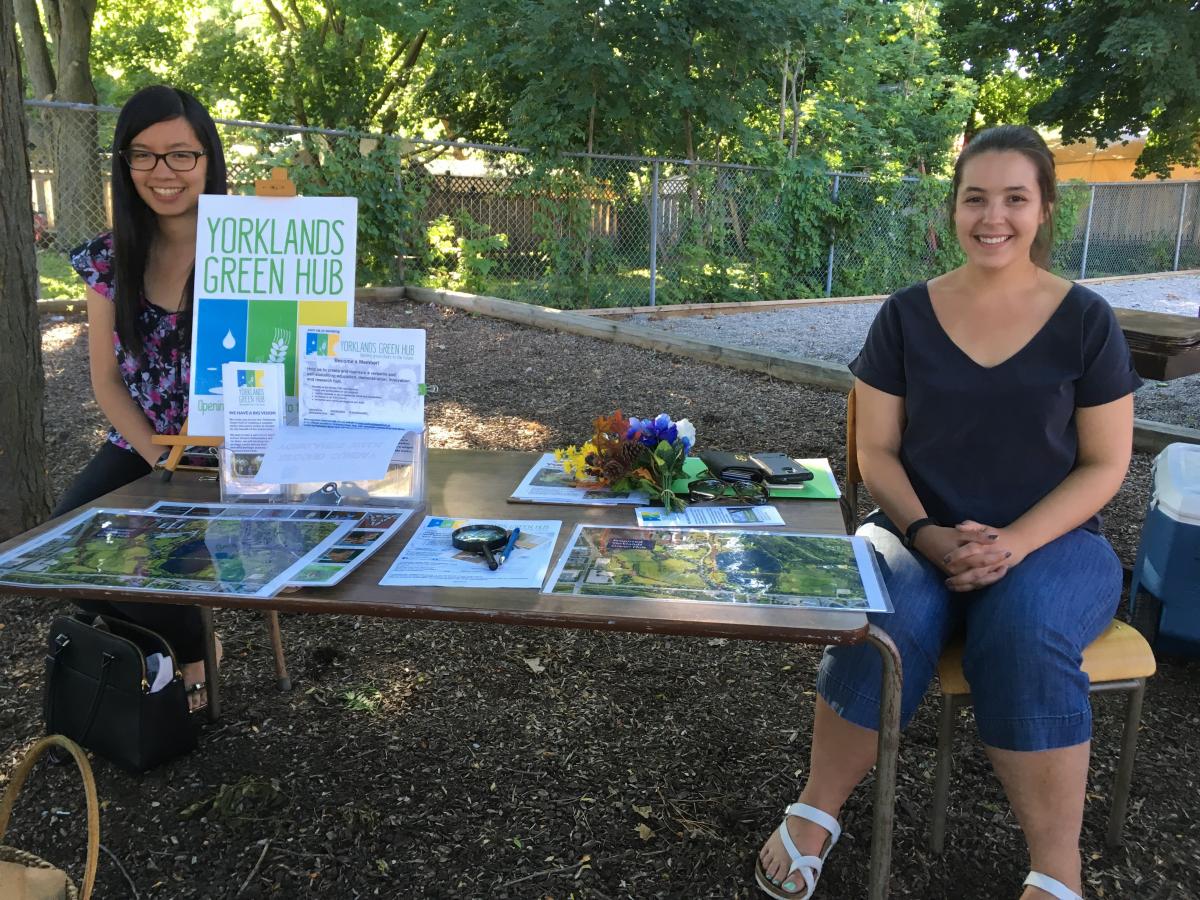 Photo of two Research Shop students sitting at a kiosk representing the Yorklands GreenHub.