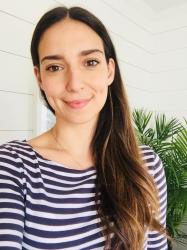 Woman with long brown hair wearing a striped shirt smiles at the camera