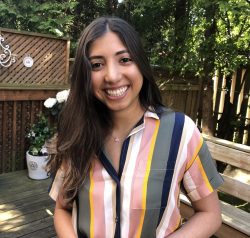 Woman with long dark hair wearing a striped shirt smiling