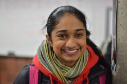 Woman with dark hair pulled back wearing a green scarf and colourful winter jacket, smiling