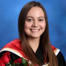 Woman with long brown hair in a graduation gown holding red roses