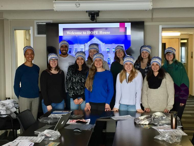 Group of nine people smiling, wearing blue hats.