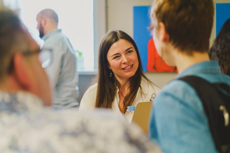 A woman with long brown hair smiles while in conversation