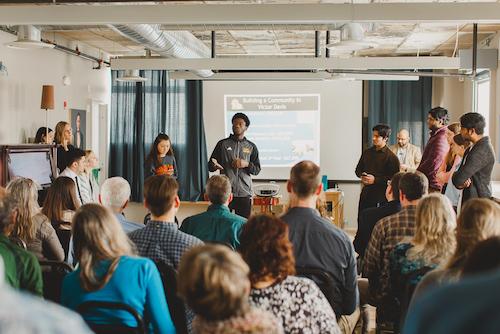 Group of people watching a presentation being given by a young man