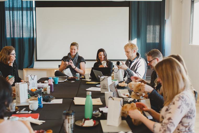 Candid shot of about 10 CESI staff sitting around a table, opening gift bags and admiring the contents