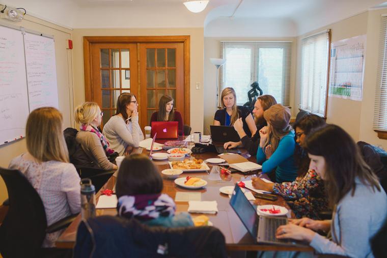 A group of young adults gathered around a boardroom table