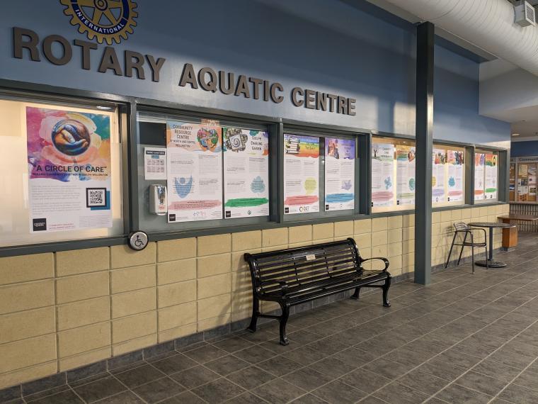 10 colourful posters displayed side-by-side on a wall with a bench underneath.