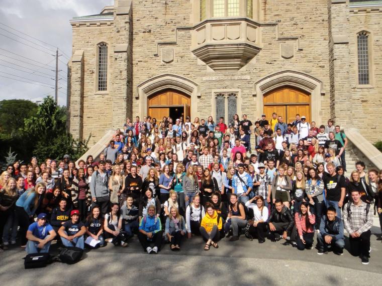 Large group of students posing in front of a building