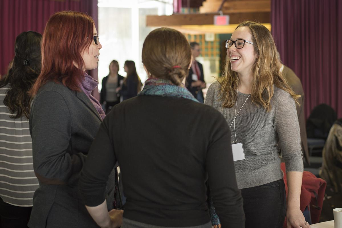 women standing in group smiling and talking at event